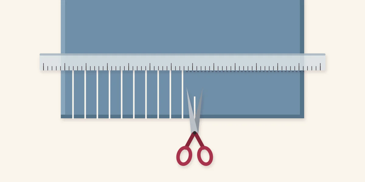 End of a fleece strip with a ruler marking the fringe depth and scissors cutting even strips