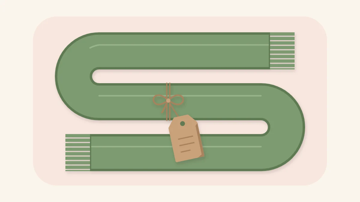 Folded sage green fleece scarf with fringed ends and a kraft gift tag