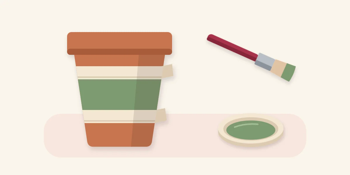 Terracotta pot with masking tape bands and a painted stripe between them, next to a brush